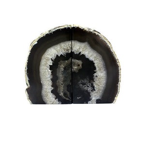 May include: A pair of agate bookends, each featuring a natural slice of agate with a black and white pattern. The agate is polished and has a smooth, glossy finish.