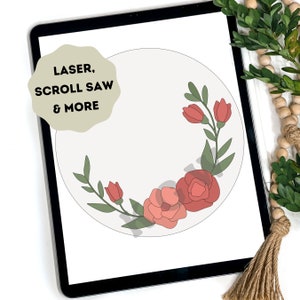 May include: Digital illustration of a floral wreath with red flowers and green leaves on a white background. The text "LASER, SCROLL SAW & MORE" is in a circle on the top left of the image.