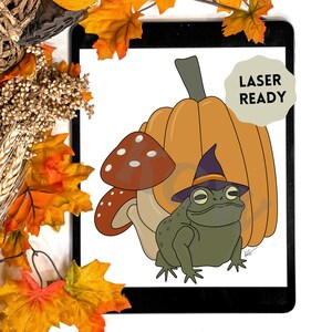 Könnte beinhalten: Eine digitale Illustration eines grünen Kröten, das einen Hexenhut trägt und neben einem Kürbis und einem Pilz sitzt. Das Bild ist mit "Laser Ready" beschriftet.