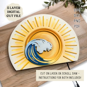 Puede incluir: Un archivo de corte digital de cinco capas con un diseño de sol y ola. El diseño tiene forma de semicírculo y presenta un sol amarillo con rayos y una ola azul. El archivo está disponible en los formatos SVG, DXF, PNG y PDF.  Corte con láser o sierra de calar - ¡se incluyen instrucciones para ambos!