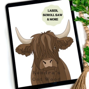 Op de afbeelding: Een digitale illustratie van een bruine Highland-koe met lang, ruig haar. De koe kijkt recht naar de kijker. De tekst "Kendra's Got Wood" staat onder de koe. De tekst "LASER, SCROLL SAW & MORE" staat in een cirkel boven in de afbeelding.