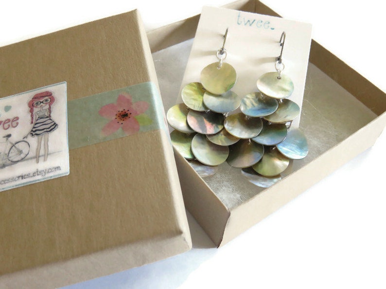 Shiny mussel shell earrings inside a brown cardboard gift box