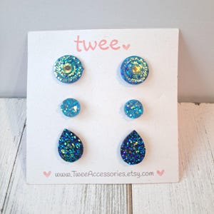 May include: A set of six blue and teal glitter earrings on a white card. The earrings are in three different shapes: round, small round, and teardrop. The card has the word "twee" and the website address www.TweeAccessories.etsy.com.