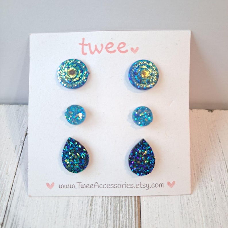 May include: A set of six blue and teal glitter earrings on a white card. The earrings are in three different shapes: round, small round, and teardrop. The card has the word "twee" and the website address www.TweeAccessories.etsy.com.