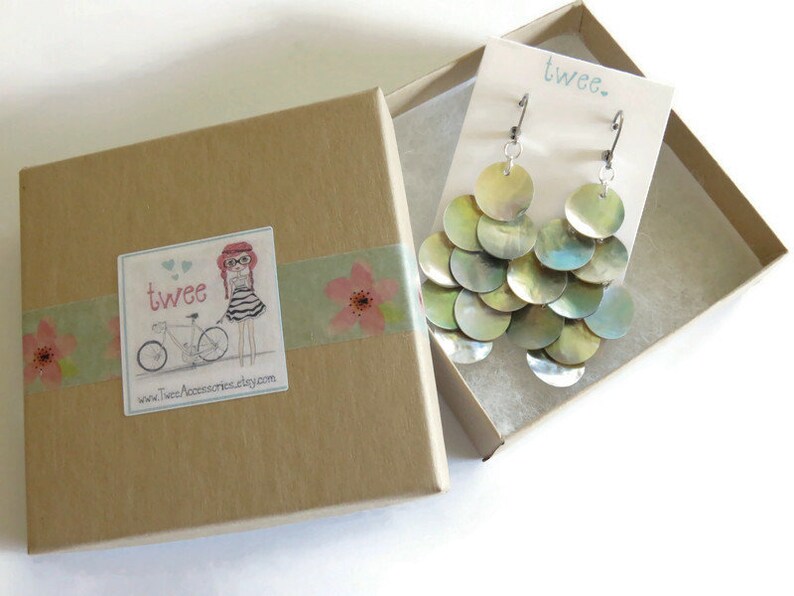 Mussel shell earrings on a display card inside a square kraft paper jewelry gift box. The box is decorated with floral washi tape and a sticker with the twee logo.