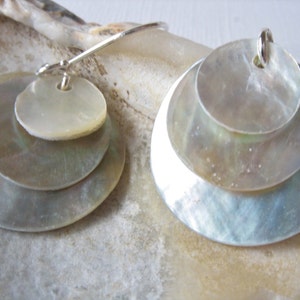 May include: A pair of silver earrings with three layers of iridescent white mother-of-pearl discs.