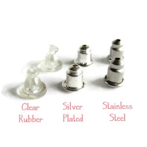 May include: An assortment of earring backs in clear rubber, silver plated, and stainless steel. The text in the image reads "Clear Rubber", "Silver Plated", and "Stainless Steel". The earring backs are displayed on a white background.
