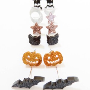 Puede incluir: Un conjunto de 10 pendientes de tem&aacute;tica de Halloween. Los pendientes presentan una variedad de dise&ntilde;os, incluyendo calaveras, estrellas, gatos, calabazas y murci&eacute;lagos. Los pendientes est&aacute;n hechos de purpurina negra, blanca, dorada y plateada.