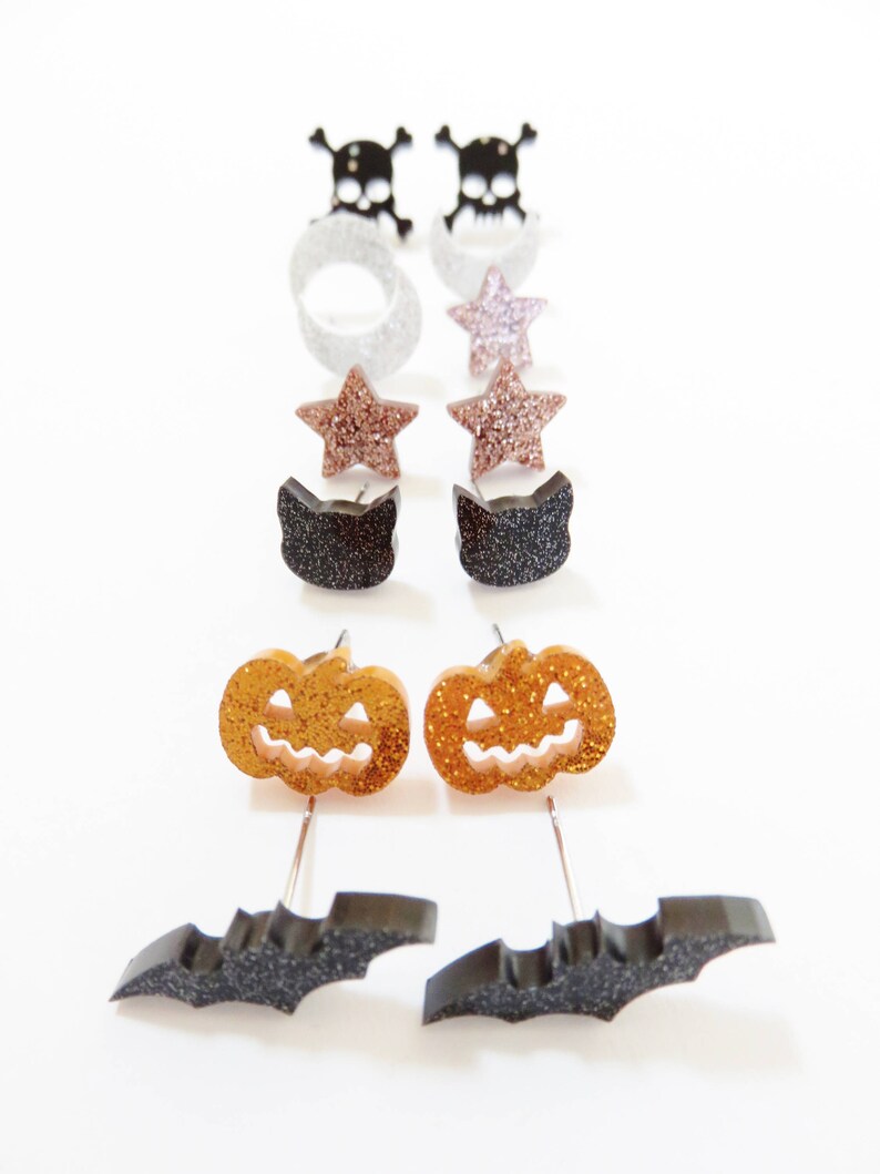 Puede incluir: Un conjunto de 10 pendientes de tem&aacute;tica de Halloween. Los pendientes presentan una variedad de dise&ntilde;os, incluyendo calaveras, estrellas, gatos, calabazas y murci&eacute;lagos. Los pendientes est&aacute;n hechos de purpurina negra, blanca, dorada y plateada.