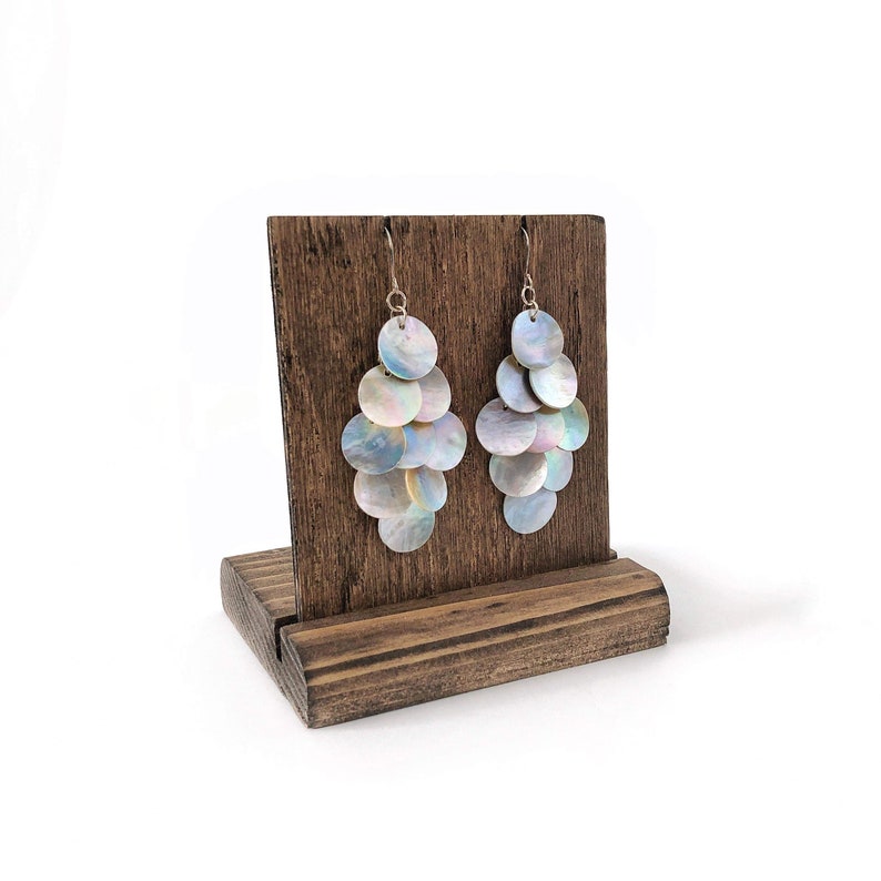 Iridescent mussel shell earrings on a wooden earring display with a white background.