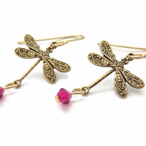 May include: Gold dragonfly earrings with dangling pink crystal accents.
