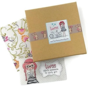 Image shows an example of packaging which includes a kraft paper jewelry box with colorful washi tape and a twee logo sticker, a twee business card, and decorative paper for a thank you note.