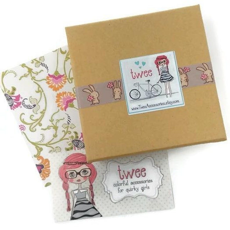 Image shows an example of packaging which includes a kraft paper jewelry box with colorful washi tape and a twee logo sticker, a twee business card, and decorative paper for a thank you note.