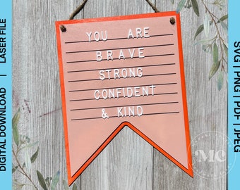 May include: A wooden sign with a peach-colored background and an orange border. The sign reads "YOU ARE BRAVE STRONG CONFIDENT & KIND" in white letters. The sign is hanging by a brown rope. The words "DIGITAL DOWNLOAD | LASER FILE" and "SVG | PNG | PDF | JPEG" are also visible.
