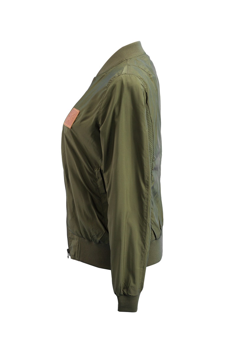 May include: A green bomber jacket with a zipper closure and a brown leather patch on the left side.