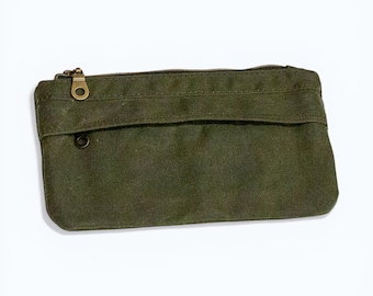 May include: An olive green rectangular pouch with a brass zipper and a small pocket. The pouch is made of a textured fabric and has a simple, minimalist design. The zipper pull is a small ring.