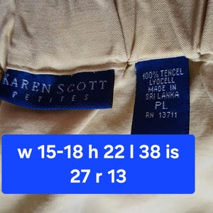 May include: Close-up of a beige garment with a blue label that reads "KAREN SCOTT PETITES". A second blue label indicates the fabric is 100% Tencel Lyocell and made in Sri Lanka. A blue rectangle displays measurements.