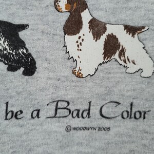 May include: A heather gray fabric featuring a black dog and a brown and white dog illustration. Below the dogs, the text reads "n't be a Bad Color" with the copyright text "&copy; WOODWYN 2005" printed underneath in black ink.