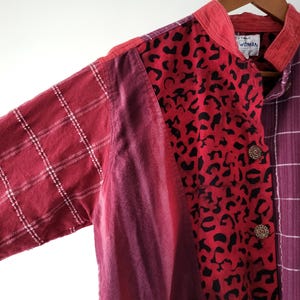 May include: A red, purple, and white patchwork shirt with a leopard print panel. The shirt has a mandarin collar and a button closure. The label reads "Woman".