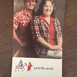 May include: A vintage Christmas card featuring a couple in plaid shirts with the text "joy to the world" and "The Klein's".