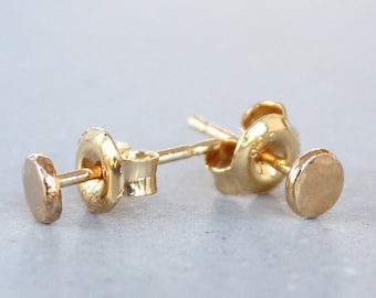 Op de afbeelding: Een paar kleine, ronde gouden oorbelletjes. De oorbelletjes zijn simpel en minimalistisch in design.