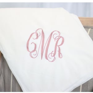 May include: White plush throw blanket with a pink embroidered monogram "CMR" in a script font.