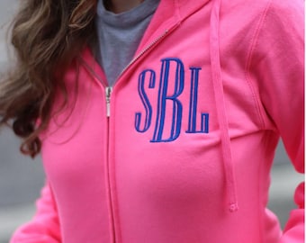 May include: A bright pink zip-up hoodie with a blue embroidered monogram "SBL" on the front.