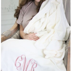 May include: A white plush throw blanket with a pink embroidered monogram "MR".