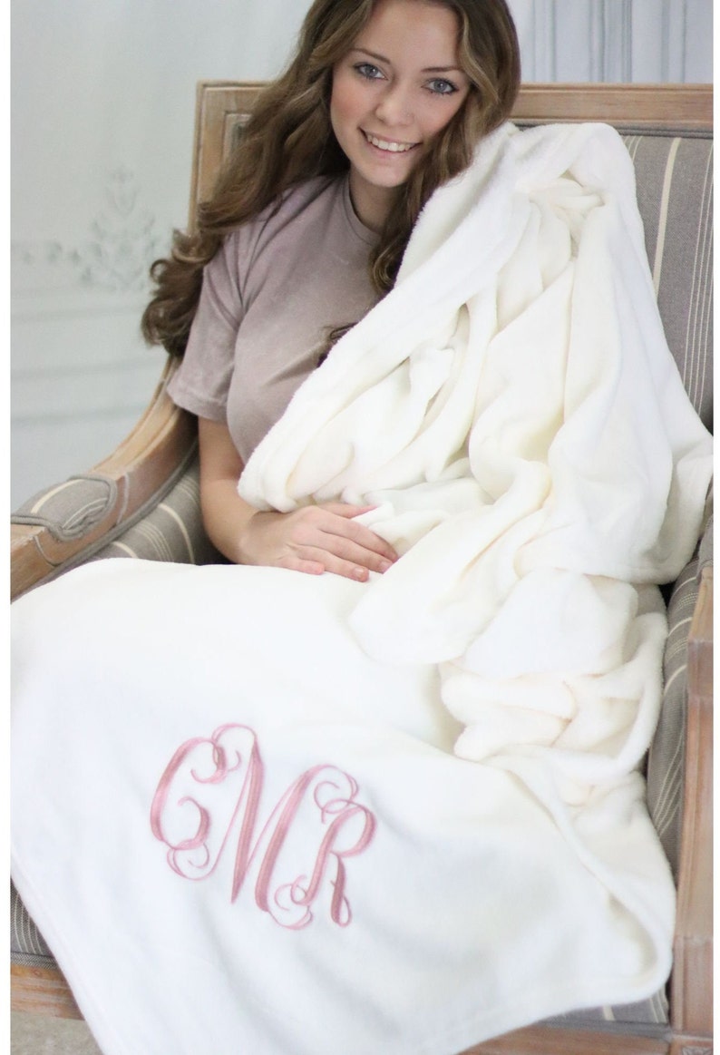 May include: A white plush throw blanket with a pink embroidered monogram "MR".
