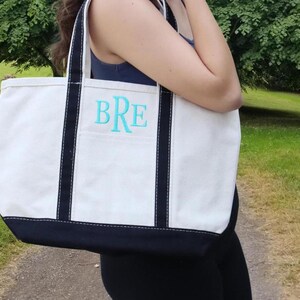May include: A white canvas tote bag with black trim and a blue monogram that says "BRE".