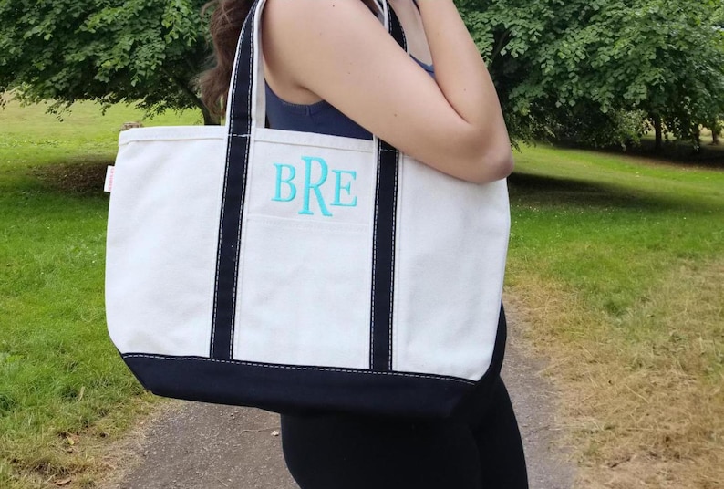 May include: A white canvas tote bag with black trim and a blue monogram that says "BRE".
