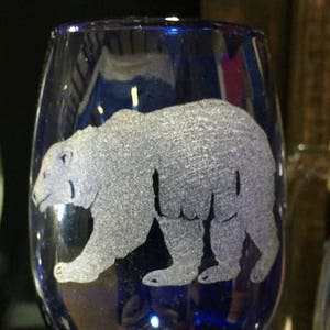May include: A cobalt blue wine glass with an etched design of a polar bear.