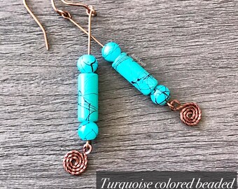 Op de afbeelding: Turquoise gekleurde kralen hangende oorbellen in koper. De oorbellen hebben een koperen draadspiraal aan de onderkant.