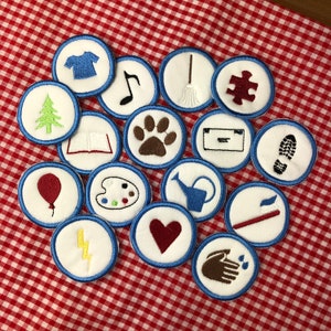 Peut inclure: Un ensemble de 15 patchs brodés thermocollants avec différents motifs, dont une note de musique, une empreinte de patte, un arrosoir, une brosse à dents, un éclair, un cœur, une palette de peinture, un livre, un arbre, une empreinte de pied, une pièce de puzzle, un balai, une chemise, un ballon et une main avec des gouttes d'eau. Les patchs sont tous circulaires et ont une bordure bleue.