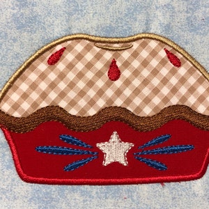 May include: A red, white, and blue embroidered pie with a gingham crust and a star in the center.