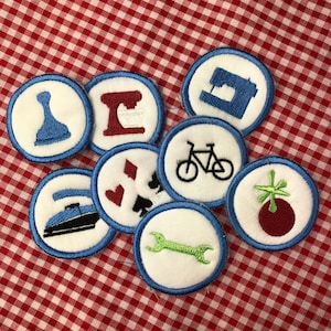 May include: Seven embroidered iron-on patches with various designs, including a sewing machine, a bicycle, a playing card, a wrench, a chess piece, a musical note, and a red berry with a green stem.