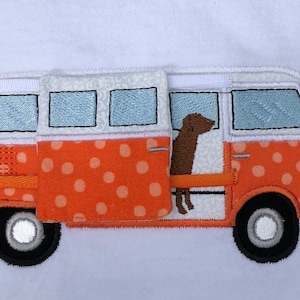 May include: A white and orange polka dot van with a brown dog sitting in the open door. The van has a white roof and blue windows.