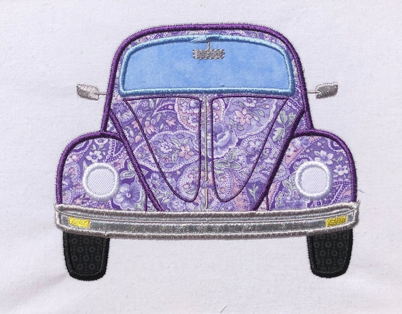 May include: Purple and white patterned Volkswagen Beetle car with a blue windshield. The car has a silver bumper and black tires.