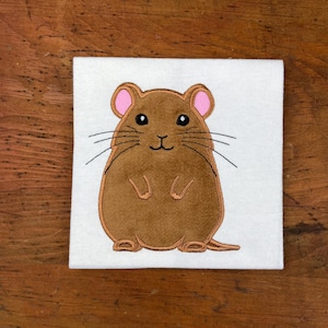 May include: Embroidered brown mouse with pink ears and black whiskers on a white background.