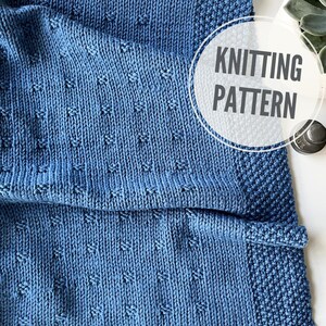 May include: A blue knitted blanket with a textured pattern. The blanket has a border with a different stitch. A white circle with the words "Knitting Pattern" is in the upper right corner.