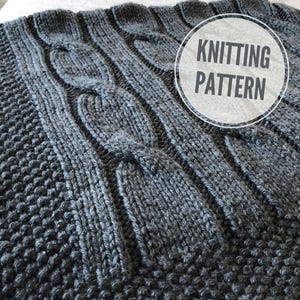 Puede incluir: Una manta gris tejida con un diseño de punto de cable. La manta presenta un patrón texturizado con secciones elevadas e entrelazadas. Las palabras "KNITTING PATTERN" están en un círculo blanco en la esquina superior derecha.