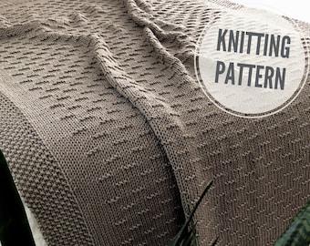 Op de afbeelding: Een close-up van een gebreide deken in een lichtbruine kleur. De deken heeft een textuurpatroon en is gevouwen op een wit oppervlak. De tekst "Knitting Pattern" is zichtbaar in een witte cirkel op de deken.