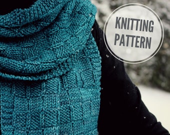 Può includere: Una sciarpa di lana blu turchese con un motivo testurizzato. La sciarpa è piegata e drappeggiata sulla spalla di una persona. Il testo "Knitting Pattern" è visibile in un cerchio nell'angolo in alto a destra dell'immagine.