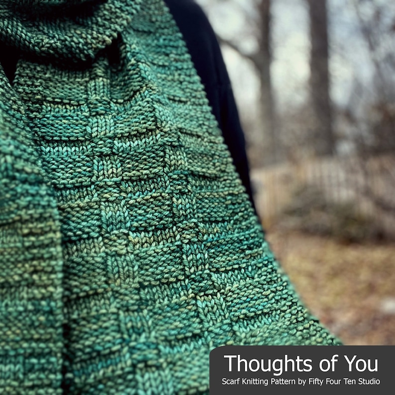 Pu&ograve; includere: Una sciarpa di lana verde con un motivo testurizzato. La sciarpa &egrave; piegata e drappeggiata sulla spalla di una persona. Il testo "Thoughts of You" &egrave; stampato sotto la sciarpa. Il testo "Scarf Knitting Pattern by Fifty Four Ten Studio" &egrave; stampato sotto il titolo.