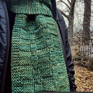 Pu&ograve; includere: Una sciarpa di lana verde e blu con un motivo testurizzato. La sciarpa &egrave; intitolata "Thoughts of You" ed &egrave; un modello di maglia di Fifty Four Ten Studio.