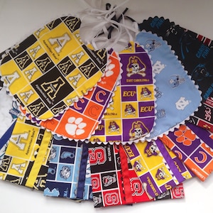 Puede incluir: Una colecci&oacute;n de 14 baberos para beb&eacute;s coloridos con varios logotipos y nombres de equipos universitarios, incluyendo Appalachian State, ECU, Carolina Panthers y NC State. Los baberos est&aacute;n hechos de tela de algod&oacute;n y tienen un borde festoneado.