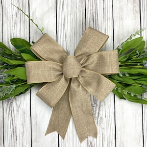 May include: A large, brown burlap bow with a simple, elegant design. The bow is tied with a single loop and has a slightly textured finish.