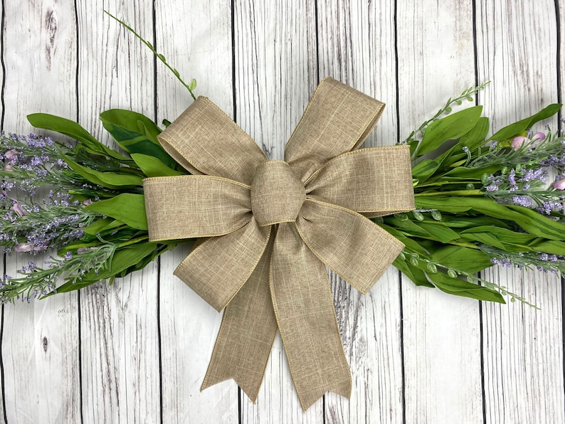 May include: A large, brown burlap bow with a simple, elegant design. The bow is tied with a single loop and has a slightly textured finish.