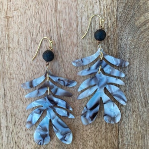 May include: A pair of dangle earrings with a gray and white marbled leaf design and black lava rock beads.