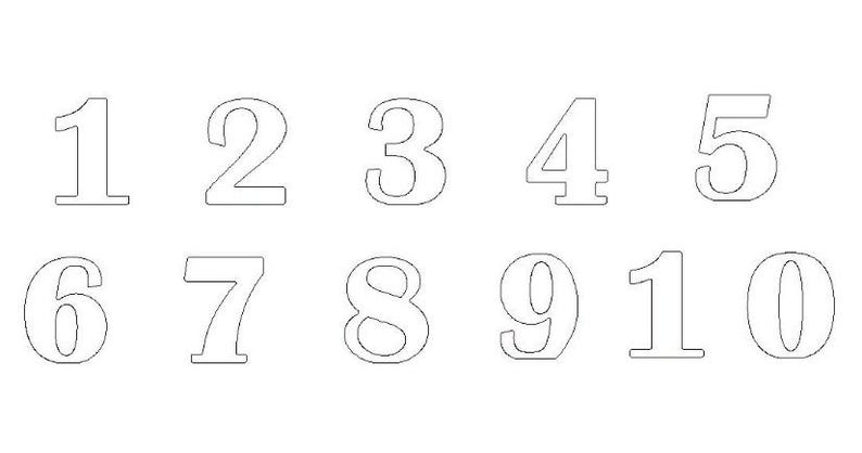 Op de afbeelding: Een set van tien witte cijfers, van 1 tot en met 10, in een eenvoudig, vet lettertype. De cijfers zijn zwart omlijnd en zijn gerangschikt in twee rijen van vijf.